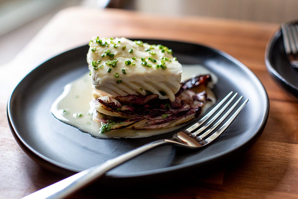 Close up of Andrew Zimmern's beautifully garnished Poached Halibut with Beurre Blanc.
