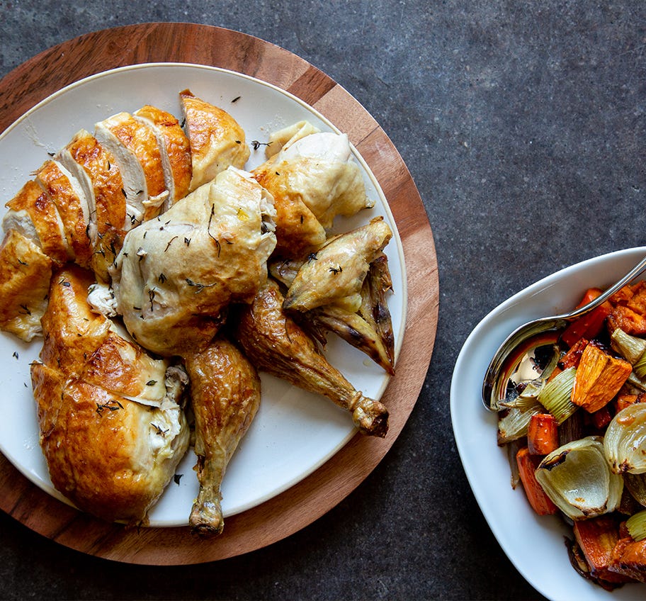 Roasted Chicken sliced on a plate with Pan Gravy and vegetables on the side